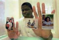 Rodney holds pictures of his children inside the visitation booth at Texas Death Row