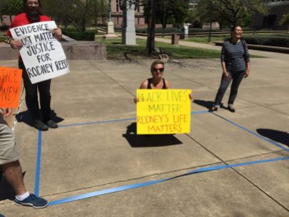 Outside the Court of Criminal Appeals, a supporter kneels inside a 6' x 10' area representing the size of cells on Texas death row